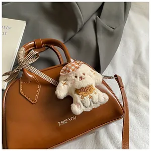 Detailed shot of brown leather bag featuring a cute plush dog charm and ribbon handle