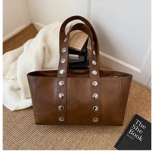 Close-up of brown vintage shoulder bag with silver metal studs on woven straw mat