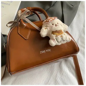 Detail of vintage brown shoulder bag with plush dog charm and plaid ribbon bow