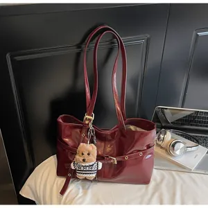 Détail du sac cabas rouge en cuir ciré avec boucles décoratives et breloque ours