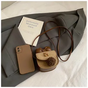 Dettaglio di una mini borsa a tracolla marrone per bambine con fiocco e ciondolo a orsetto