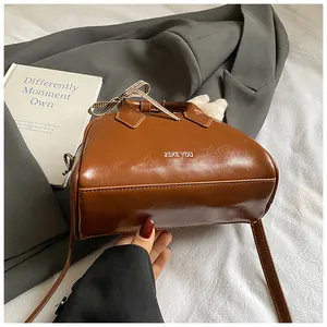 Detailed view of a vintage brown boston bag with stylish checkered bow and slim leather strap