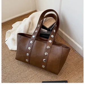 Detail of dark brown tote bag with silver rivets on woven mat in cozy setting
