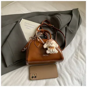 Detailed view of a brown vintage leather handbag featuring a plush dog charm and ribbon