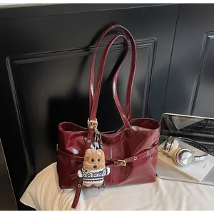 Détail du sac cabas en cuir ciré bordeaux avec breloque ours et boucle latérale