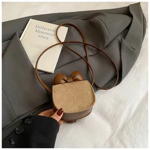 Dettaglio mini borsa a tracolla marrone con fiocco decorativo e patta testurizzata
