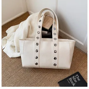 Detailed view of cream PU leather tote with silver stud accents and pebbled texture