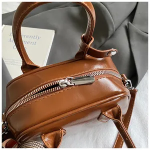 Close-up of the silver metal zipper and stitching on the vintage brown leather bag