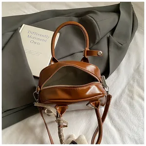 Detail of vintage brown mini barrel bag with ribbon on textured white bedding
