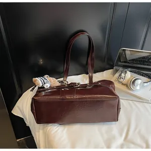 Vue détaillée du sac cabas marron foncé en cuir ciré avec boucle en métal et charm d'ourson