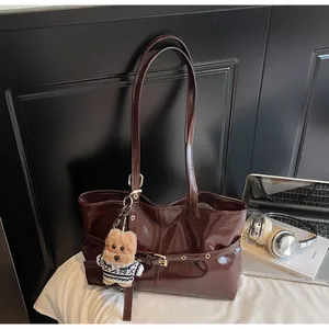 Détail du cabas en cuir ciré brillant avec boucle métallique et breloque ours en peluche