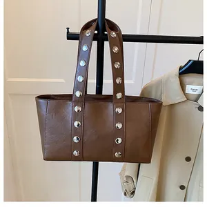 Detail of dark brown leather tote bag featuring vintage silver metal rivet accents