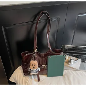 Détail du cabas en cuir ciré brun-rouge avec breloque ours et boucle de ceinture