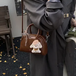 Retro brown bowling handbag with plush charm and ribbon, worn with a winter coat