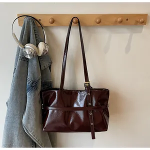 Détail du sac cabas en cuir ciré bordeaux avec texture brillante et œillets en métal