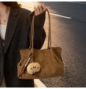 Detail of brown faux suede tote bag with plush charm on a grey wool coat model