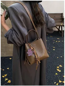 Brown crocodile embossed bucket bag detail with leopard bear charm in autumn street setting