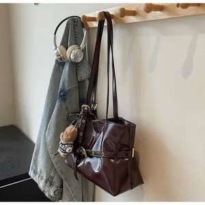 Détail du grand sac cabas marron foncé en cuir huilé avec boucles dorées et charm ours