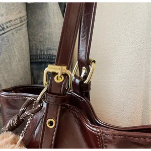 Détail du cabas en cuir ciré bordeaux avec boucle dorée et breloque en peluche