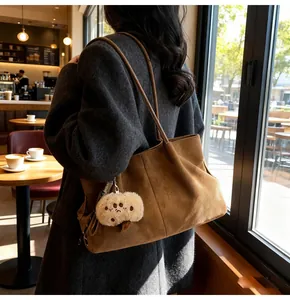 Close-up of brown suede tote bag with plush charm in a minimalist cafe setting