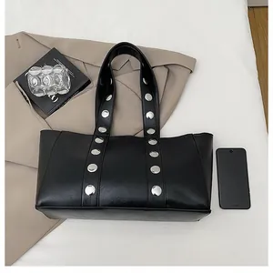 Detail shot of black PU leather tote bag with stylish large silver metal rivets