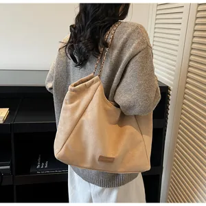 Détail du sac cabas en suédine avec bandoulière en chaîne dorée et fini texturé