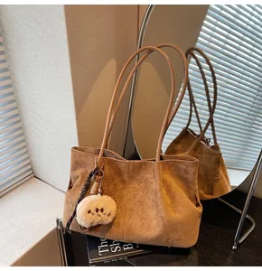 Detail of brown faux suede tote bag with slim straps and a cute plush bear charm