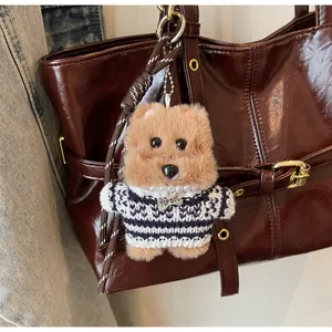 Pendentif chien en peluche avec pull rayé sur un grand sac cabas marron poli