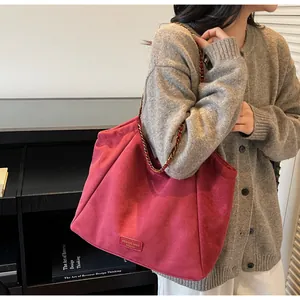 Détail du sac cabas en similicuir rose foncé avec bandoulière chaîne dorée et logo
