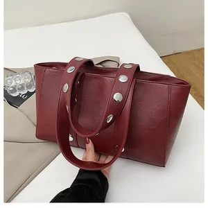 Detail showing deep red leather texture and large silver metal rivets on shoulder strap