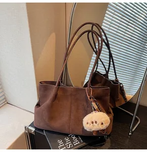 Detail of dark brown suede tote bag with white plush cloud pendant and stitched details