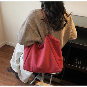 Détail d'un grand sac fourre-tout rouge avec bandoulière chaîne et étiquette en cuir