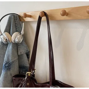 Détail du cabas en cuir ciré foncé avec boucle métallique suspendu à un crochet