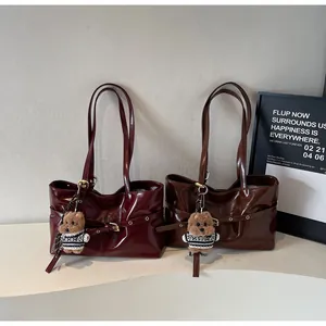 Détail de sacs cabas en cuir ciré bordeaux et marron avec pendentifs ours en peluche