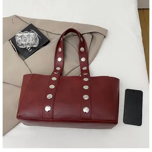 Detail of dark red tote bag with silver rivets and spacious leather interior for daily use