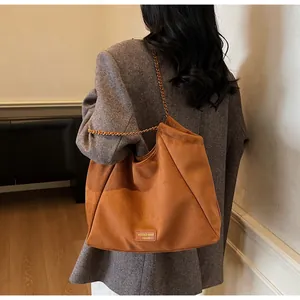 Vue détaillée du sac cabas en daim caramel avec bandoulière chaîne et plaque de marque