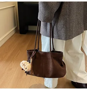 Close-up of vintage brown suede shoulder bag with soft texture and plush doll accessory