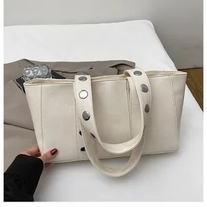 Detail view of cream PU leather tote bag with large silver buckles and rivets