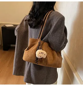 Detail of vintage brown faux suede tote bag with plush charm on casual shoulder strap