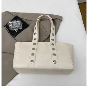 Detail view of cream white tote bag with metallic silver studs on soft leather strap