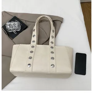 Detail of cream PU leather tote bag with silver metal rivets on the shoulder strap