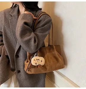 Detail view of brown suede hobo bag with retro texture and plush charm accessory