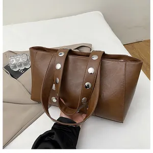 Detailed close-up of silver metal rivets on a brown leather shoulder bag handle