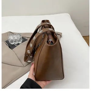 Detail of dark brown retro tote bag featuring stylish silver rivets on a wide shoulder strap