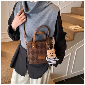 Detailed shot of a brown quilted tote bag with suede texture and cute bear charm pendant