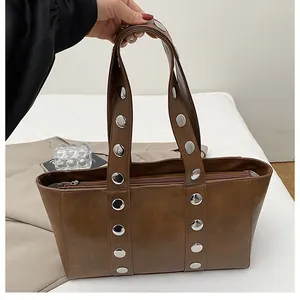 Detail of brown faux leather shoulder bag featuring decorative silver metal studs and zipper