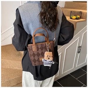 Detail of dark brown argyle quilted tote bag with leather handles and cute bear charm