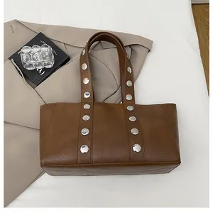 Detail view of vintage brown tote bag with silver metal studs and long shoulder straps
