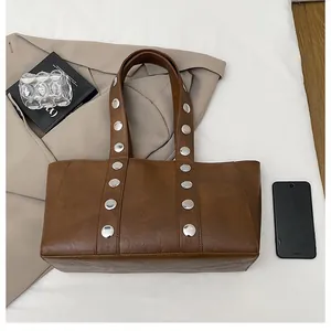 Close-up of brown large tote bag with silver rivets and litchi grain texture