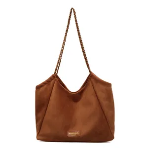 Sac fourre-tout en daim marron avec bandoulière chaîne et logo doré sur blanc
